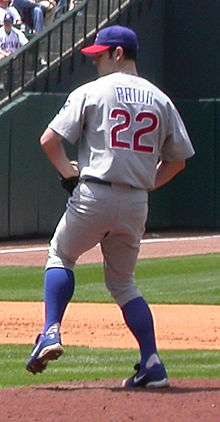 A view of a man in a grey baseball jersey on a mound of dirt preparing to throw a pitch. The back of his jersey says "Prior", with the number 22.