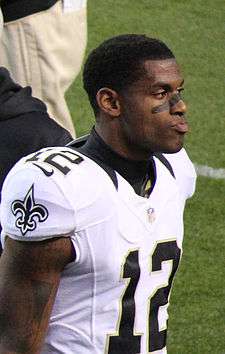 A dark-skinned man wearing a white football jersey