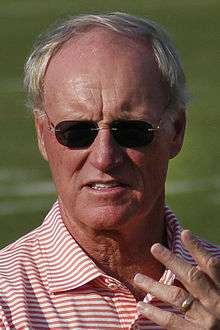 Unposed head and shoulders photograph of Schottenheimer wearing a red and white striped polo shirt and dark sunglasses