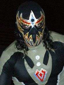 Máscara Dorada, wearing his trademark black and gold mask that covers his entire face except his eyes.