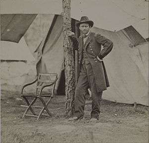 Grant in a standing position is leaning on a tree during the Battle of Cold Harbor.