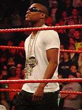 Mayweather, wearing sunglasses, white T-shirt and chains, in wrestling ring with red ropes