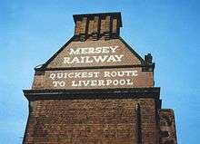 A painted sign on the side of a building with the following text in capital letters: "Mersey Railway" "Quickest route to Liverpool".