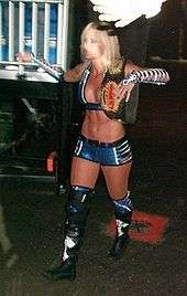 Michelle McCool walking towards the ring with the WWE Women's Championship belt over her shoulder.