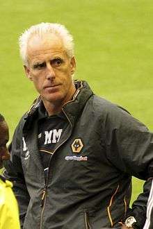 A man wearing a black waterproof jacket, with the Wolverhampton Wanderers logo on the left side