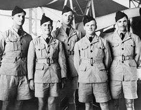 Five men in light-coloured military uniforms with dark forage caps