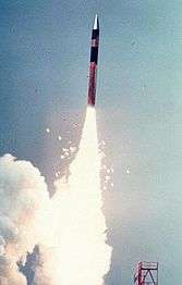 Portrait photo of missile firing its rocket motors shortly after launch.