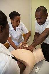 Women receiving training in midwifery, using a model, in Papua New Guinea