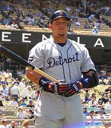 A man in a grey baseball uniform with the word "Detroit" written across the chest holding a baseball bat.