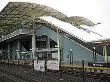 An at-grade train station situates behind two train tracks