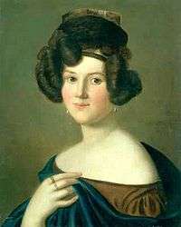 The head and upper torso of a young white woman with dark hair done in an elaborate style. She wears a small hat, a cloak and dress that expose her shoulders and pearl earrings. On her left hand that holds the edge of the cloak, two rings are visible.
