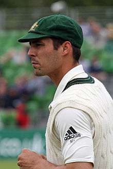 Mitchell Johnson stands side on with his body pointing left. His hands are together and his look looks concentrated.