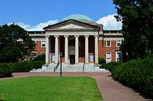  A brick building with a rusted dome and ionic columns.