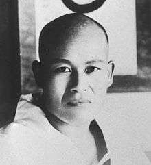Portrait of a young Japanese man with a shaved head staring into the camera