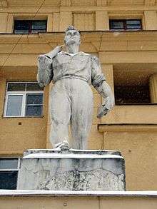 Statue of worker in front of tan apartment building