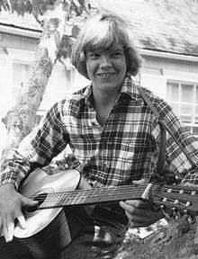 Johnny Doran sitting in a tree and playing guitar.  Approximately age 15.