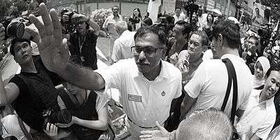 Pillai waving while being surrounded by a crowd