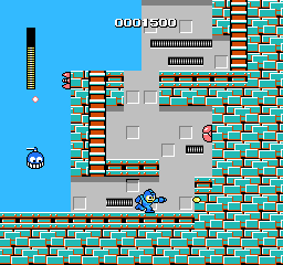 A square video game screenshot that depicts a blue character sprite firing a shot toward a vertical brick wall. Other sprites surround the character and a score are visible at the top of the screenshot.