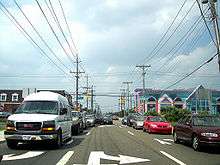 A congested one-way road facing traffic. The road is lined by power lines and businesses.