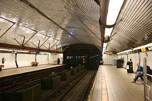 A subway station with two platforms and two tracks under a curved ceiling