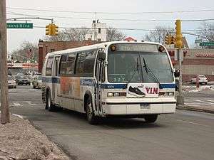 a bus in Q46 service on a large road in Kew Gardens Hills, Queens, during the winter