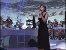 A woman in a black dress performing in a Christmas decorated stage