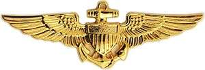 A golden badge depicting a shield superimposed over an anchor and a pair of wings
