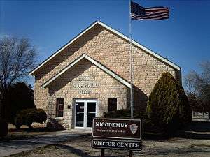 Photograph of the Township Hall in Nicodemus Historic District on a sunny early spring day, with a national park visitor center sign in front.