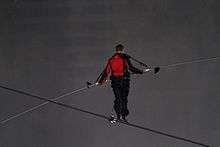 A man in black and red on a tightrope