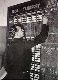 Man in dark-coloured military uniform writing on blackboard
