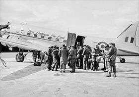 Uniformed personnel boarding a twin-engined transport plane