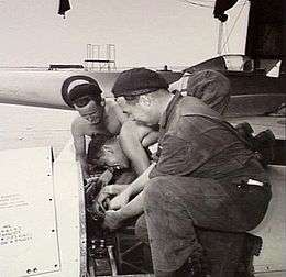 Three men in overalls working on an aircraft engine