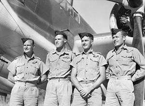 Four men in summer military uniforms with forage caps in front of a Bristol Beaufort bomber
