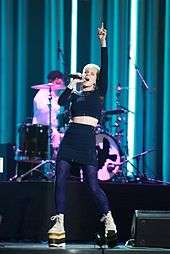 Robyn onstage in black, pointing up
