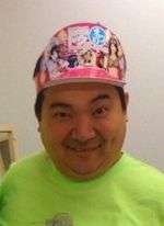 A smiling Asian man in a cap