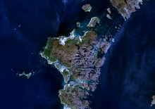 An indistinct image from space of brown and green islands in dark blue water.