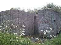 A rear view of an eastern Command Type pillbox showing the huge blast wall covering the entrance.