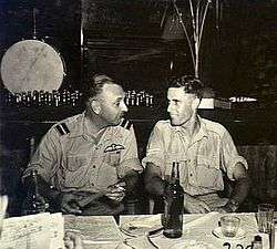Informal half portrait of two men in tropical military uniforms at a table