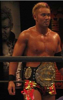 Kazuchika Okada with the IWGP Junior Heavyweight Championship belt in a wrestling ring