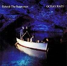 An album cover showing four men in a rowing boat inside a blue lit sea cave. Two men are stood side-by-side at the back of the boat each holding an oar, the third man is sat in the centre of the boat and the fourth is leaning over the front of the boat with his hand in the water. The band's name is in the top-left of the cover and the album's name is in the top-right, both in white text.