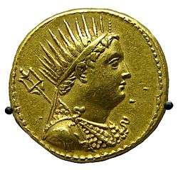 A gold coin shows the profiled bust of a man. The man is wearing a crown and drapery.