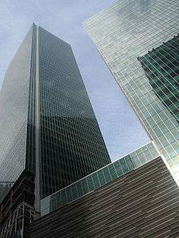 Ground-level view of two square buildings with identical all-glass facades