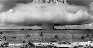 Photograph of a mushroom cloud explosion in a tropical setting