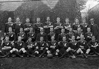 A large group of rugby players posing in three rows wearing their playing uniform