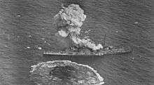 Aerial view of a cloud of smoke rising from a battleship at sea