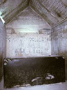 Small stone chamber, its walls inscribed with hieroglyphs and its gabled roof covered with painted stars. At the center is a massive but broken black sarcophagus.