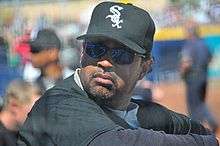 Close up of dark skinned man with a beard and mustache wearing sunglasses and a White Sox cap