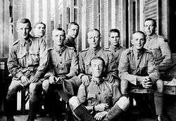 Informal portrait of nine seated men in military uniforms
