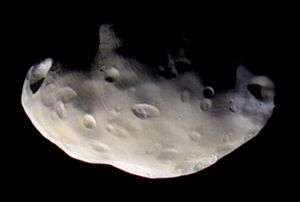 An irregularly shaped body is half illuminated from the bottom. The terminator runs from the left to right. The surface is covered by numerous craters.