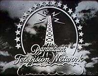 A stylized broadcasting tower atop a mountain high above the clouds, surrounded by a halo of 20 stars. Four lightning bolts emit from the top of the tower. The logo is superimposed over stormy clouds.